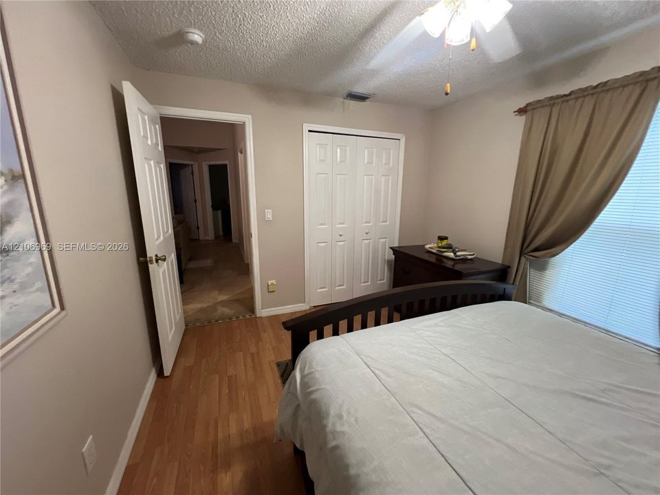 Wood-finish flooring, white panel closet doors, ceiling fan with integrated lighting, and neutral wall tones