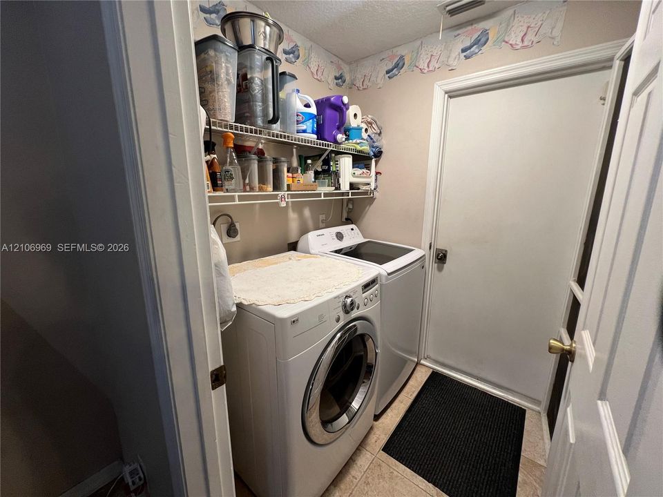 Utility area featuring white wire shelving and tile flooring