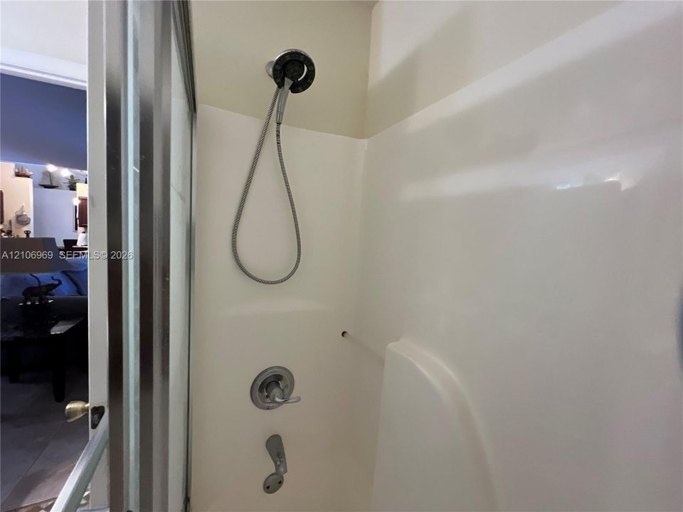 Shower enclosure featuring a multi-setting handheld showerhead, chrome-finished mixing valve, and tub spout with a polished finish
