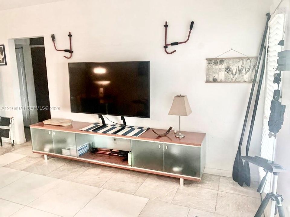 Large format tile flooring with white plantation shutters and built-in glass-front cabinetry