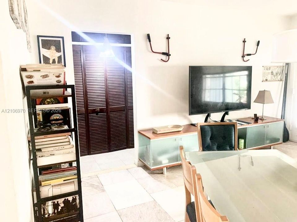 Custom built-in cabinetry with frosted glass panels and wood-tone surfacing, paired with dark-stained wood louvered closet doors and neutral tile flooring