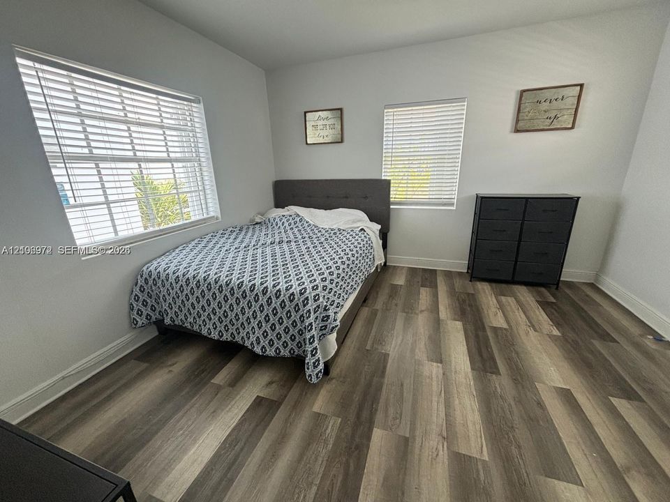 Room featuring wood-finish flooring, dual windows with horizontal blinds, and neutral wall tones