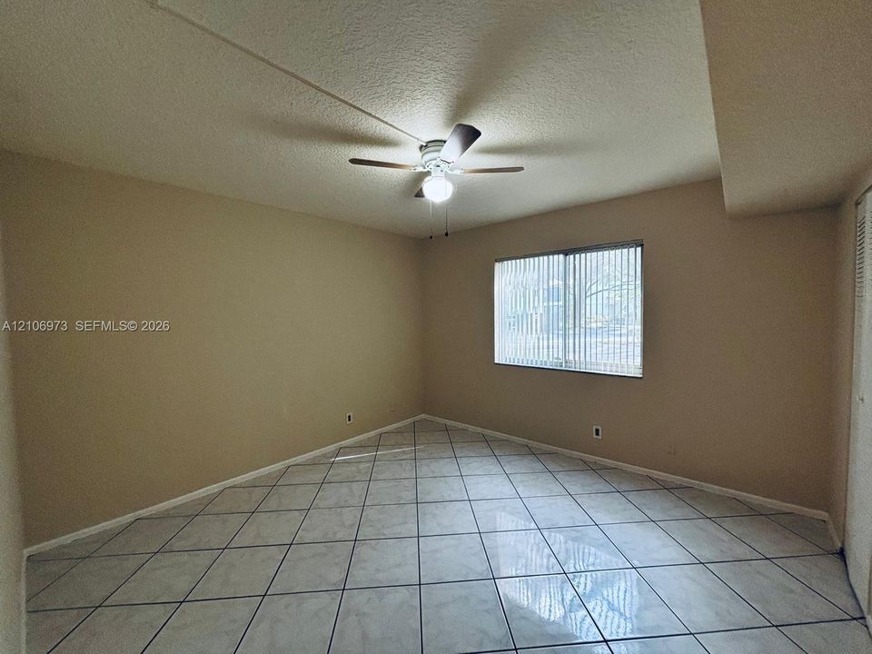 Interior space featuring large-format diagonal tile flooring, a multi-blade ceiling fan with integrated lighting, and a window with vertical blinds