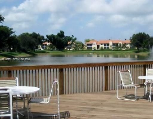 Wood-surface deck featuring a horizontal-slat wooden railing overlooking a pond with a water feature
