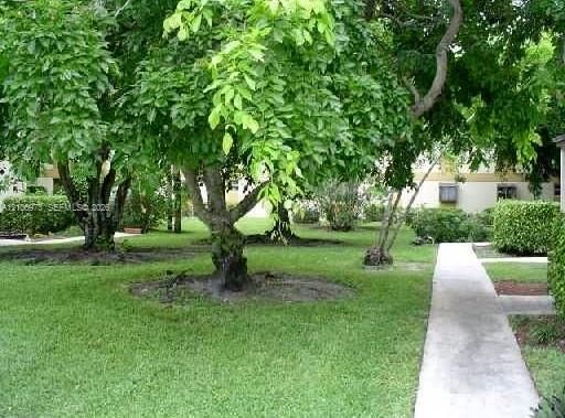Landscaped grounds featuring manicured turf, mature deciduous trees, and concrete pathways