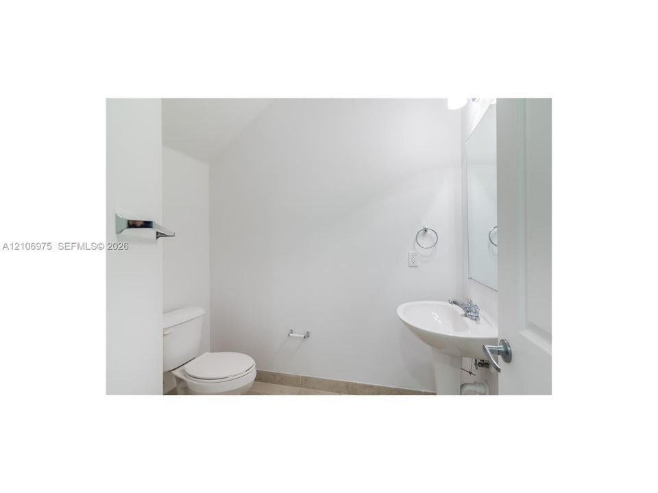 Pedestal sink featuring a chrome faucet, wall-mounted mirror, and white commode