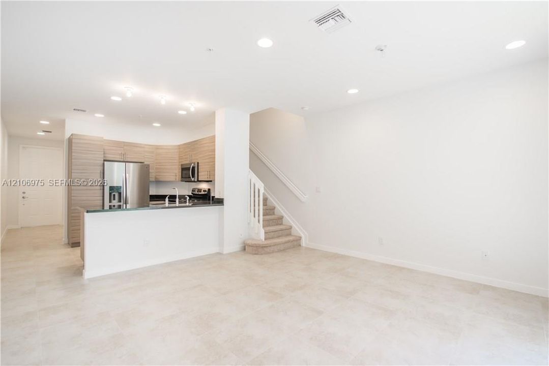 Kitchen featuring wood-finish cabinetry, stone-surfaced peninsula, stainless steel appliances, recessed lighting, and tile flooring