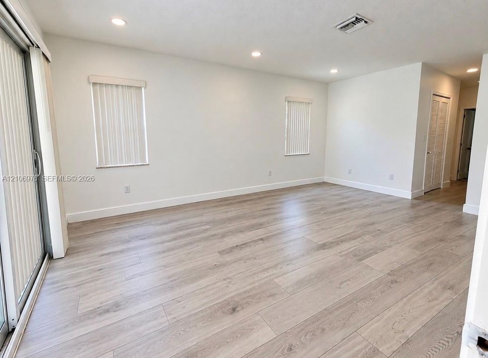Interior space featuring wood-finish flooring, recessed lighting, sliding glass door, and louvered-style closet doors