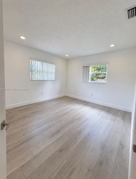 Interior space featuring wood-finish flooring, recessed lighting, and dual windows with vertical blinds