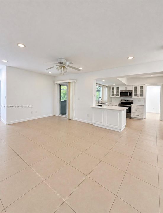 Spacious open-concept living area featuring neutral tile flooring throughout, recessed ceiling lighting, and a ceiling fan