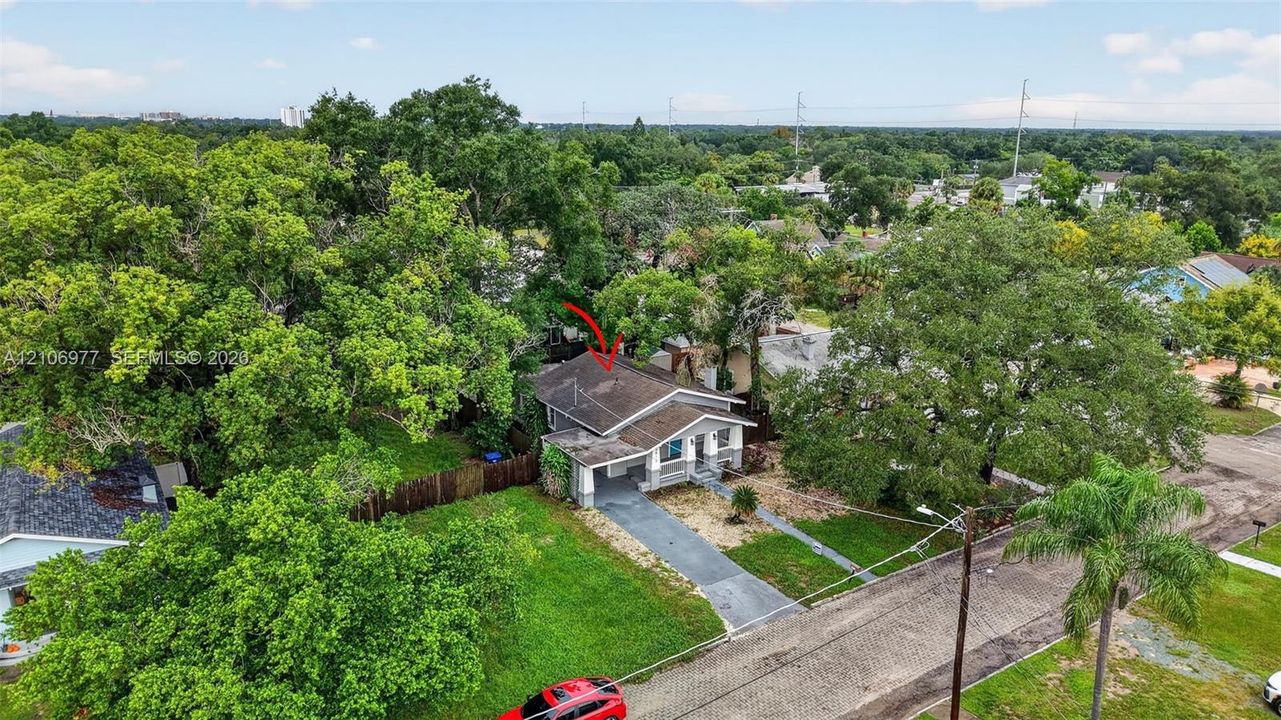 Single-story residence featuring a covered front porch, asphalt shingle roof, paved driveway, and mature landscaping on a corner lot
