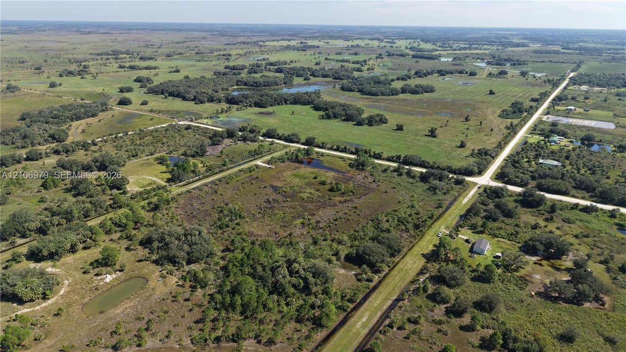 Aerial perspective of expansive acreage featuring diverse topography, natural vegetation, scattered ponds, and open pastureland