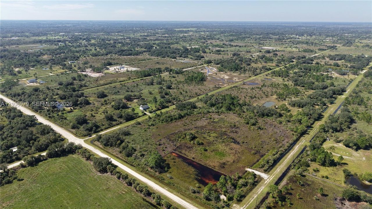 Aerial perspective of expansive acreage featuring native vegetation, mature trees, and a natural pond