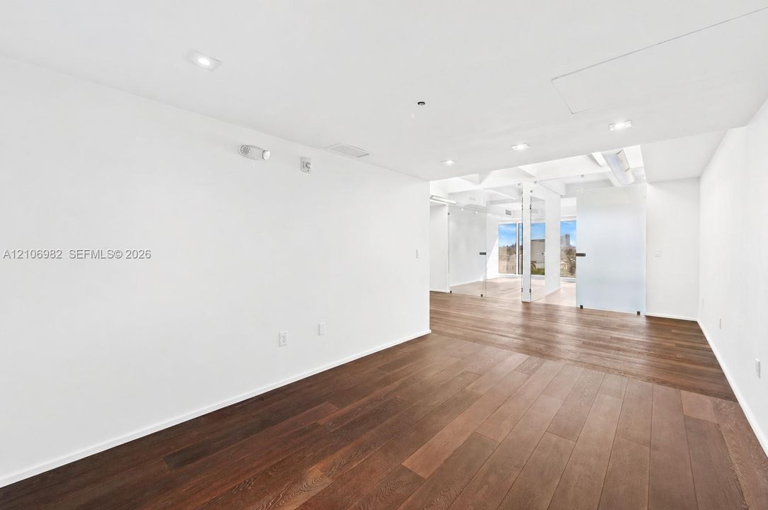Wide-plank wood-finish flooring, recessed ceiling lighting, and glass-paneled interior partitions