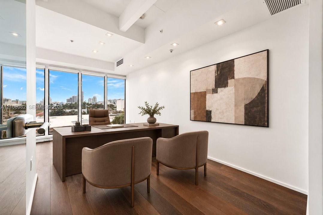 Floor-to-ceiling windows with skyline views, dark wood-finish flooring, recessed lighting, and exposed structural ceiling beam