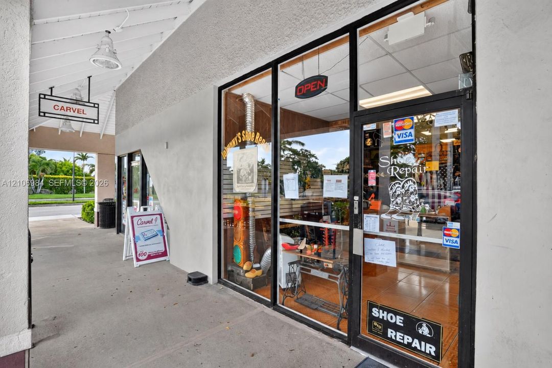 Commercial storefront featuring a full-height glass facade, aluminum framing, covered concrete walkway, and recessed overhead lighting