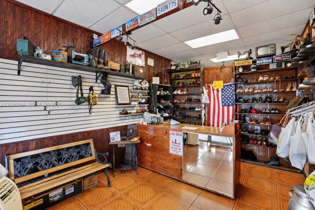 Commercial interior featuring horizontal slat-wall shelving, custom wood-finish cabinetry, built-in wooden display shelving, drop-ceiling lighting, and patterned ceramic tile flooring