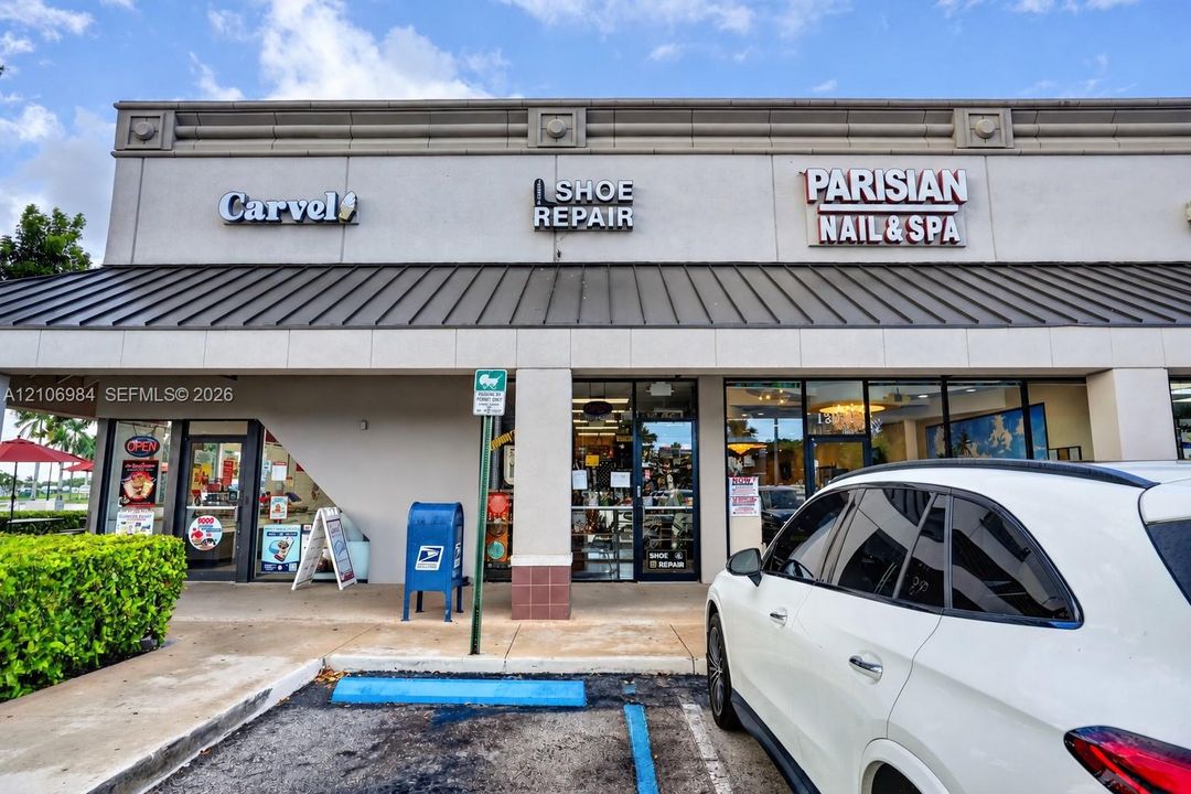 Single-story commercial retail frontage featuring a metal shed roof, stucco exterior finish, plate glass storefront windows, and dedicated exterior signage space
