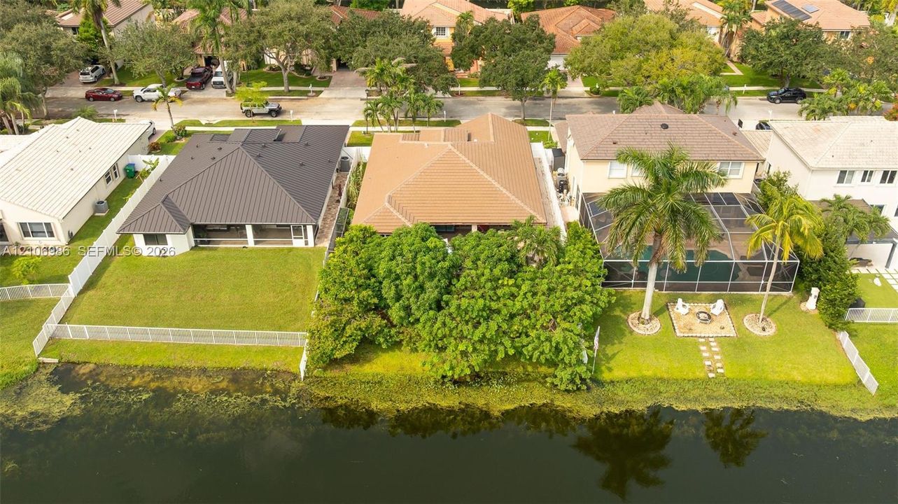 Waterfront residential lot featuring a manicured lawn, established landscaping, and perimeter fencing