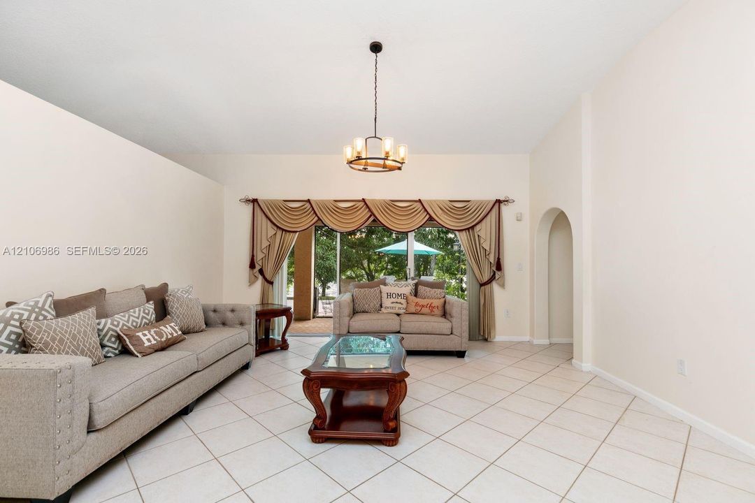 High ceilings with a central chandelier, ceramic tile flooring, and an arched architectural opening
