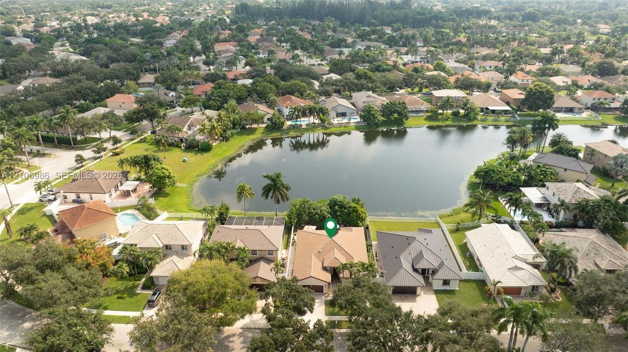 Aerial perspective featuring a waterfront property with a concrete tile roof, paved driveway, and mature landscaping