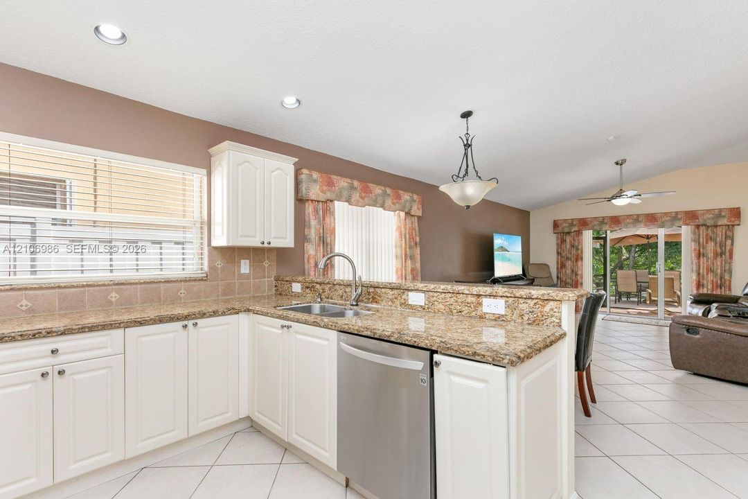 Kitchen featuring white cabinetry, stone-surface countertops, tile flooring, recessed lighting, and a stainless steel dishwasher