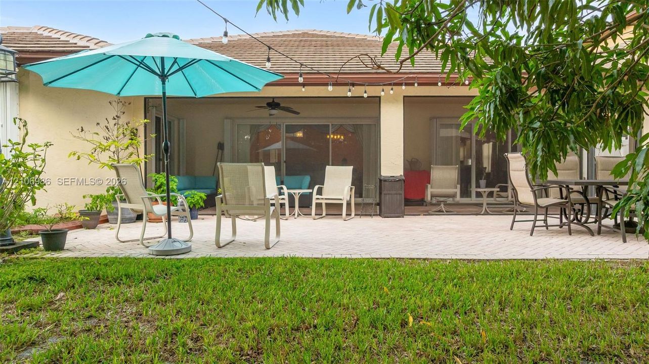 Paver patio with a covered lanai featuring a ceiling fan and sliding glass door access