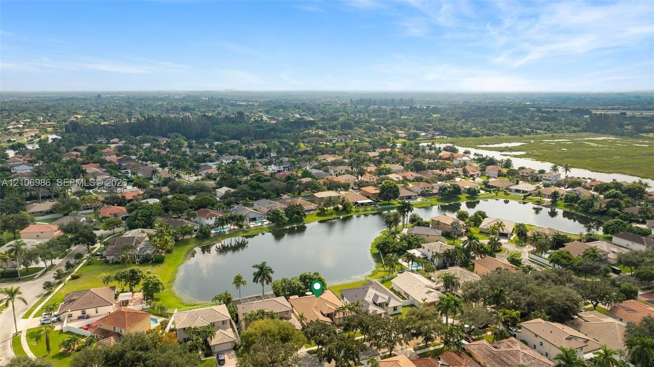 Aerial perspective featuring a single-story residence situated on a waterfront lot with mature landscaping