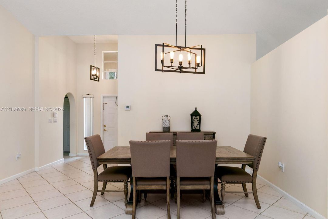 Vaulted ceilings featuring geometric metal chandeliers, ceramic tile flooring, and an arched entryway