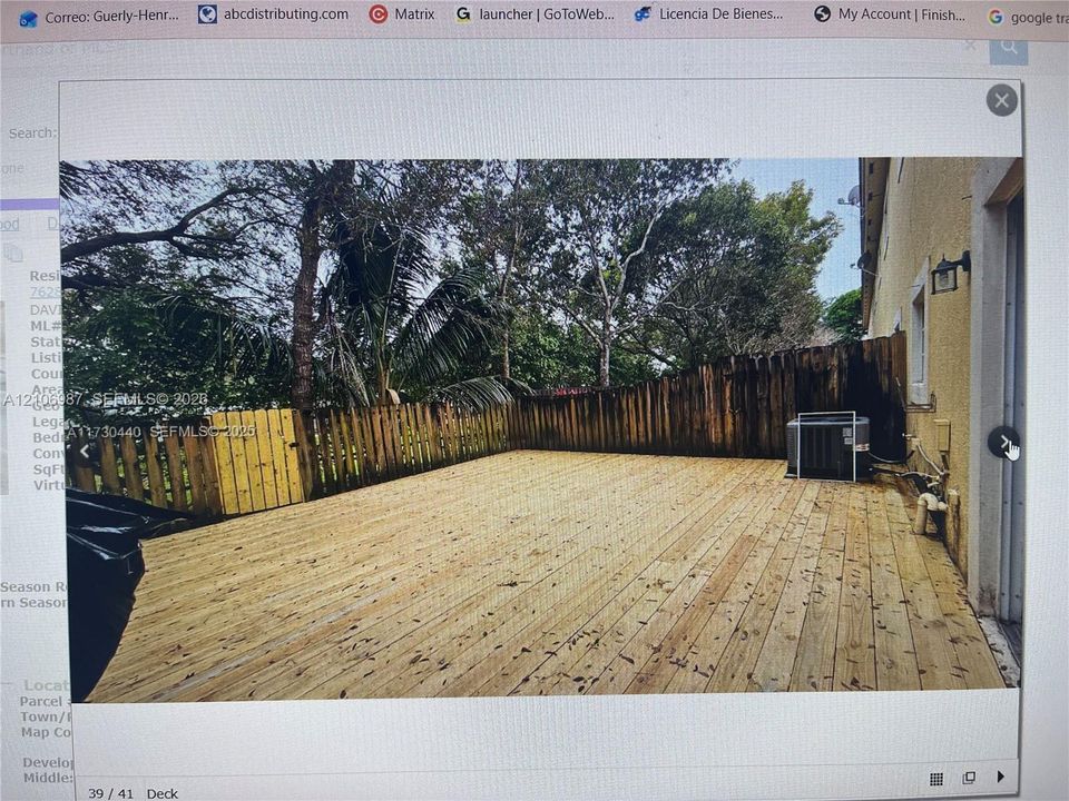 Expansive wood-finish deck bordered by a privacy fence and mature trees