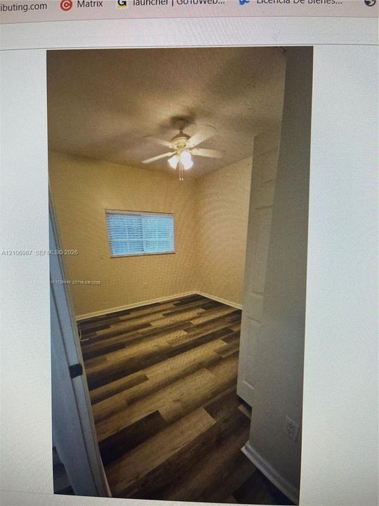 Wood-finish flooring, ceiling fan with integrated lighting, horizontal blind, and interior door with paneled detailing