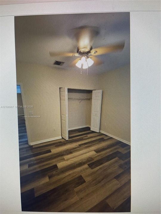 Interior space featuring wood-finish flooring, a ceiling fan with integrated light fixture, and a closet with bifold doors