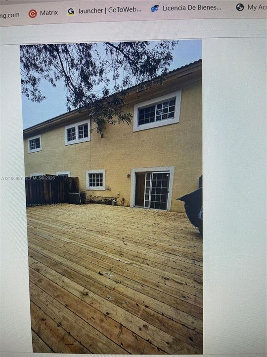 Expansive wood-finish deck spanning the rear exterior, featuring multi-lite sliding glass doors and white window trim
