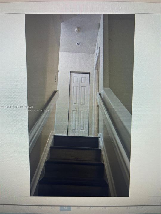 Staircase featuring wood-finish treads, white painted railings, and a bi-fold closet door