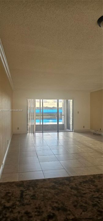 Interior space featuring large-format neutral tile flooring and sliding glass doors leading to an exterior balcony
