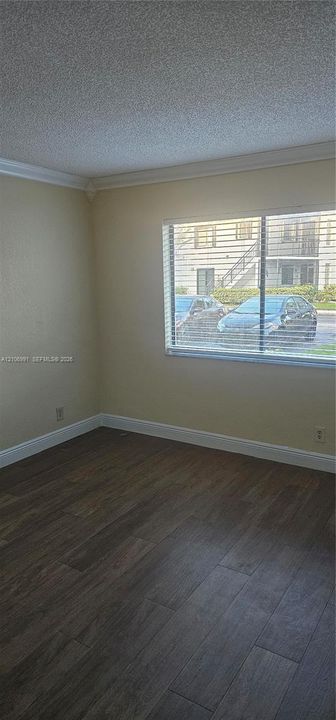 Interior space featuring wood-finish flooring, crown molding, and horizontal slat window blinds