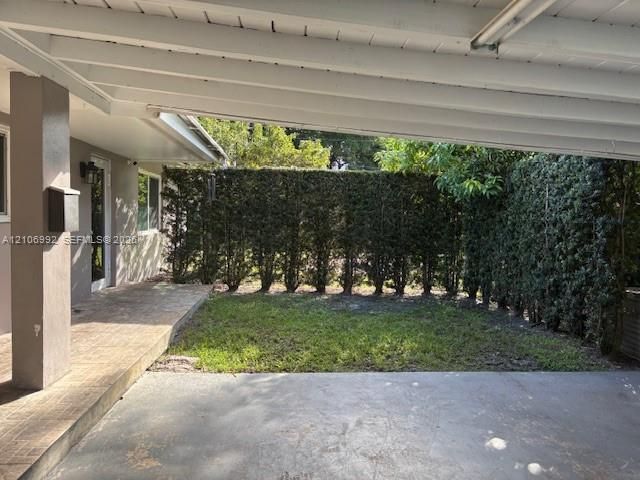 Covered patio featuring a tiled floor, concrete landing, and mature hedge perimeter