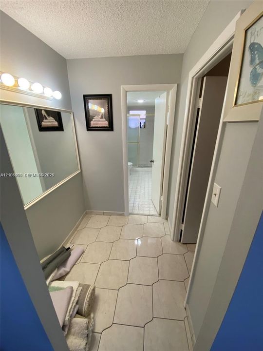Wall-mounted mirror with a five-light vanity fixture and large-format ceramic tile flooring