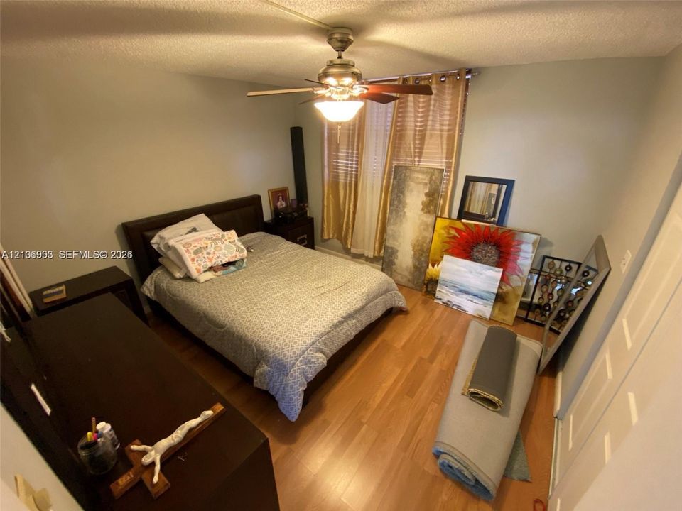 Wood-finish flooring, ceiling fan with integrated lighting, and multi-panel closet doors