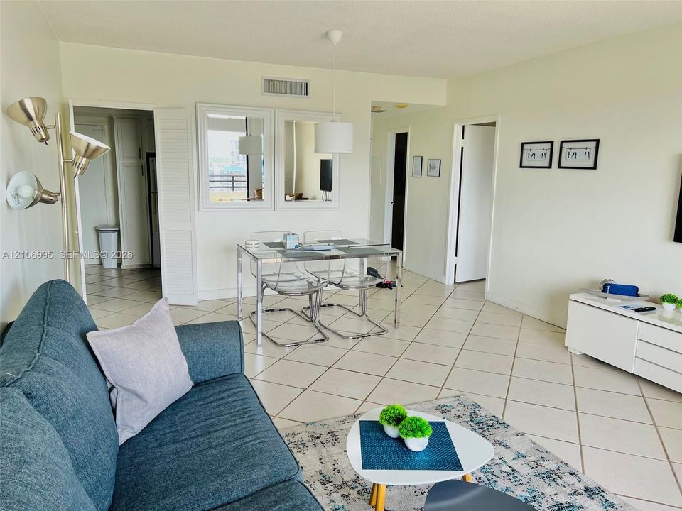 Open-concept interior featuring neutral tile flooring laid on a diagonal, dual wall-mounted mirrors, and an adjustable pendant lighting fixture