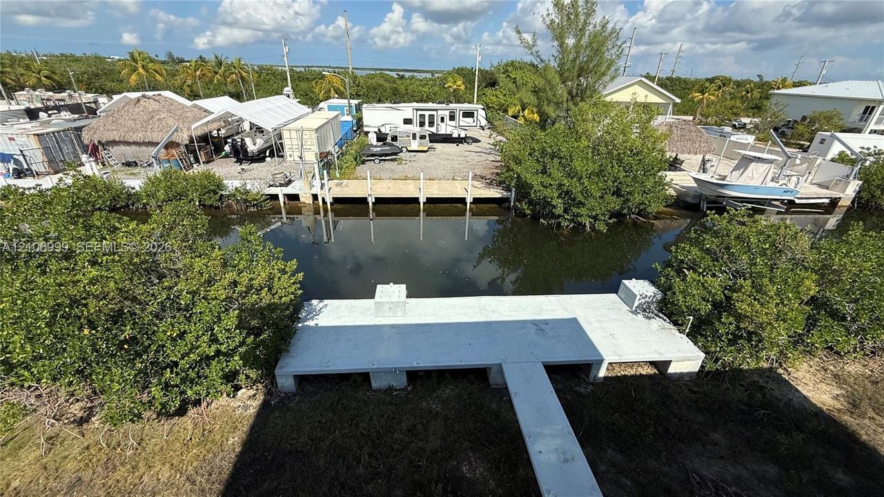 Waterfront property featuring a concrete T-dock, seawall, and access to a canal