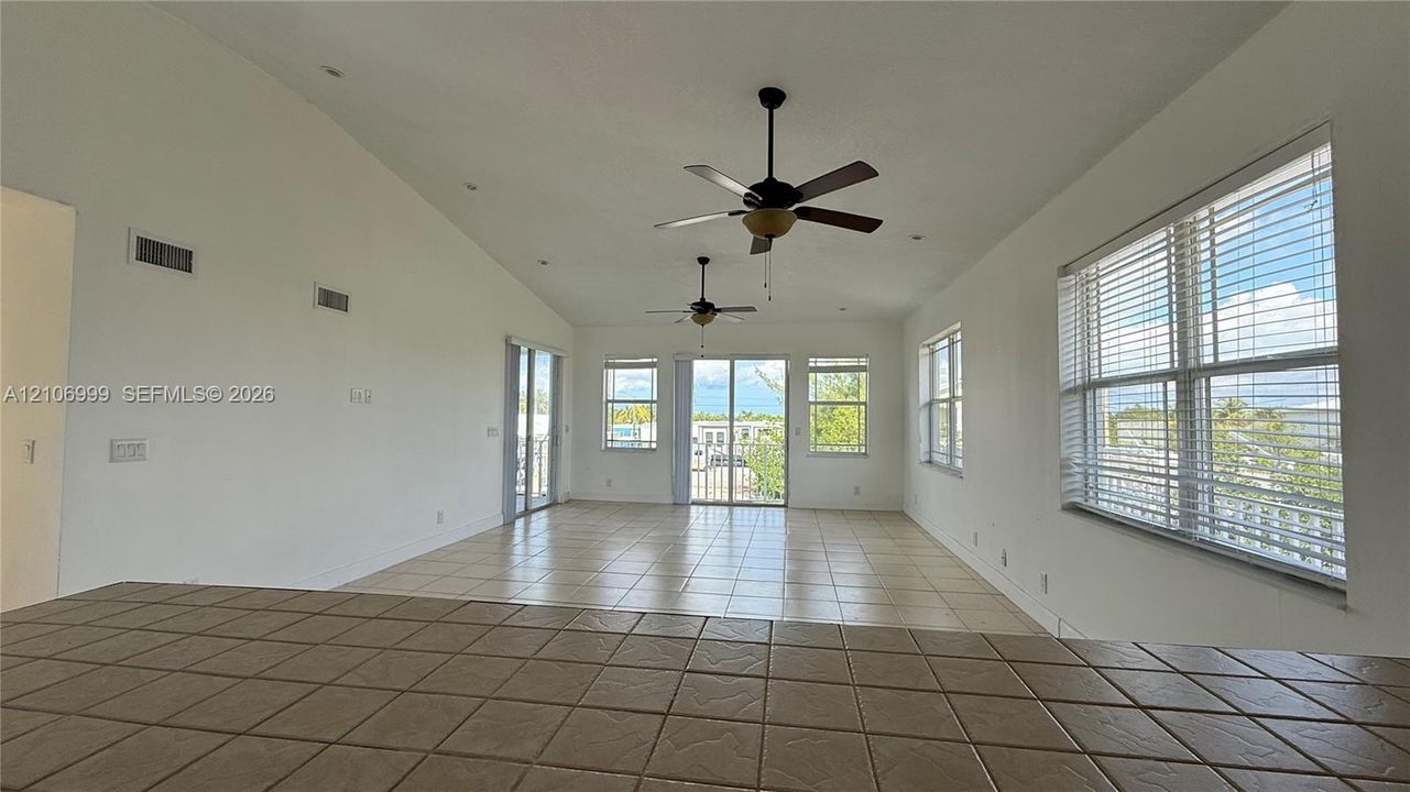 Vaulted ceilings, tile flooring, dual ceiling fans, and multiple large windows with integrated blinds