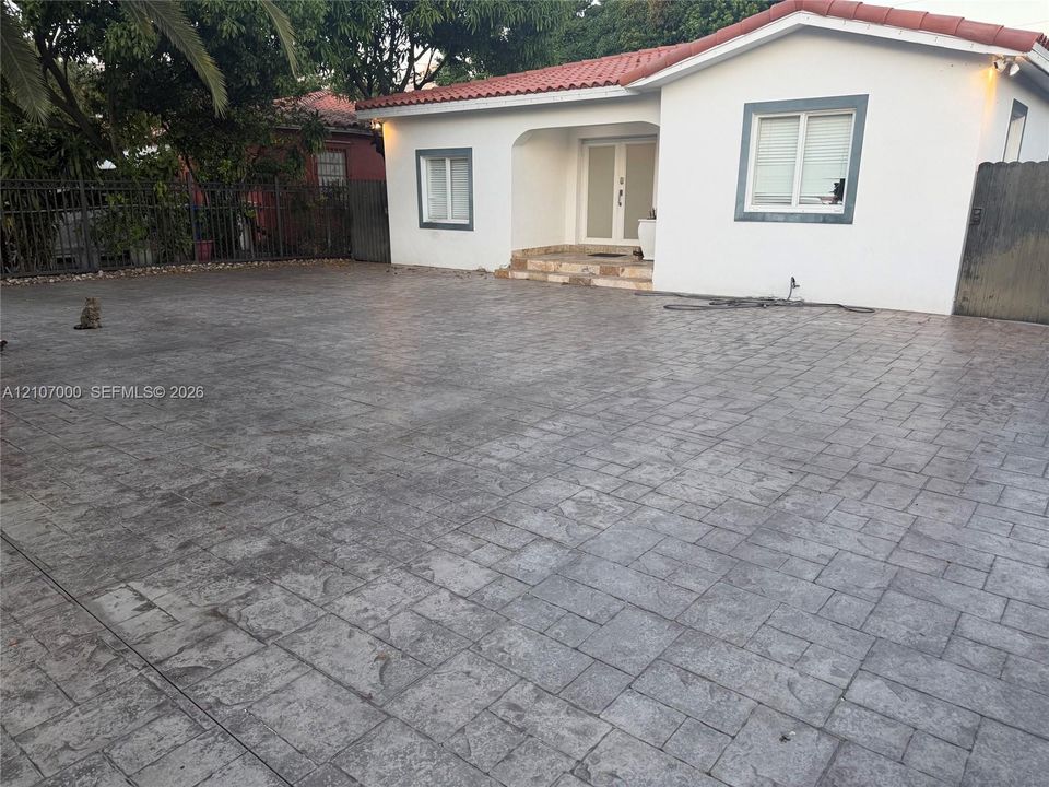 Exterior featuring a stamped concrete driveway, white stucco facade, tile roof, and double-entry doors
