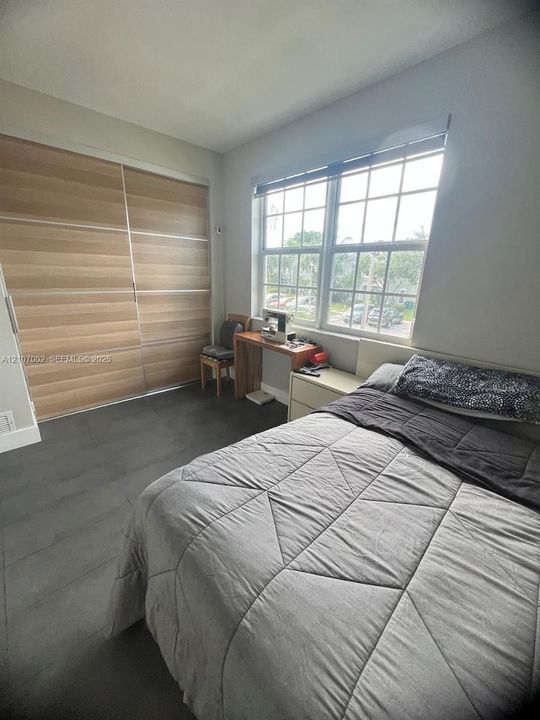 Large multi-panel windows with muntins, floor-to-ceiling sliding closet doors with wood-finish panels, and neutral floor tiling