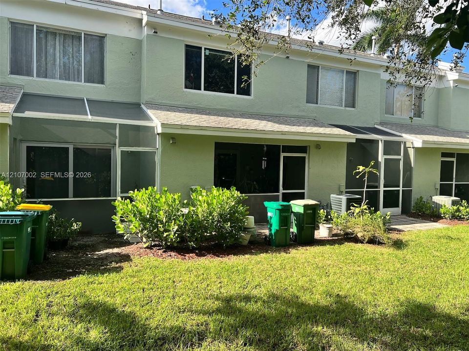 Stucco exterior featuring dual-level windows, a screen-enclosed patio, and asphalt shingle roofing