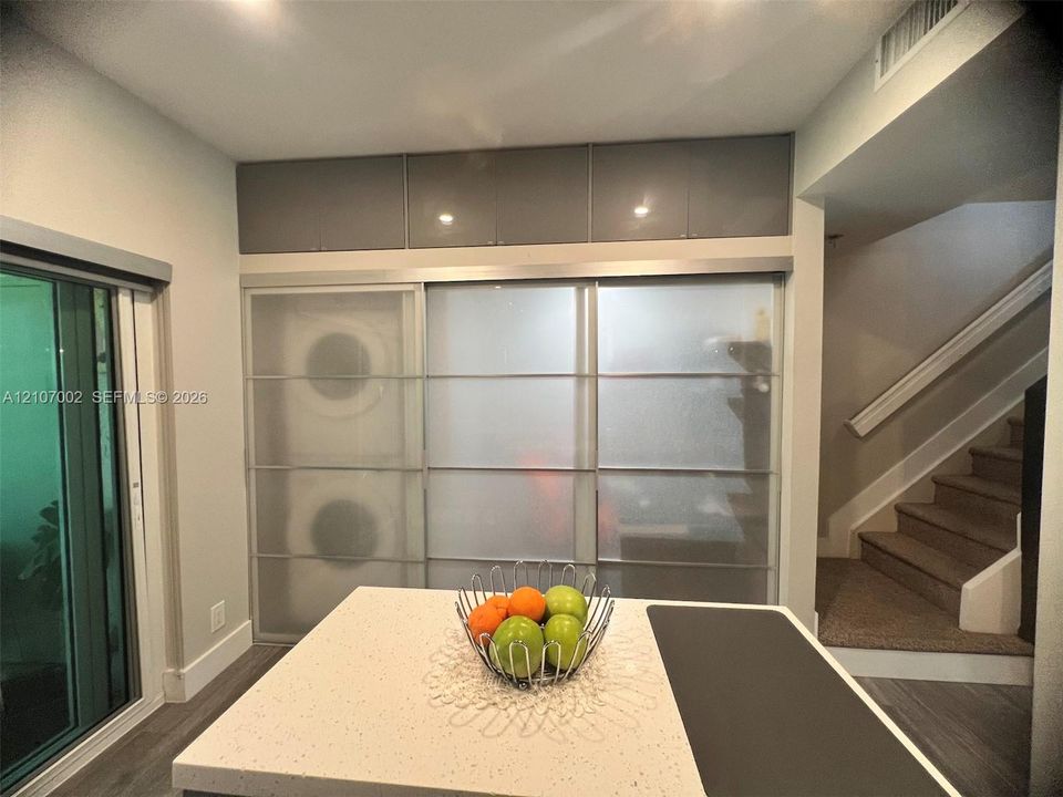 Kitchen island with stone-finish countertop, translucent sliding panel doors, high-gloss overhead cabinetry, and wood-finish flooring