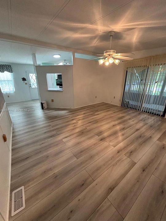 Wood-finish flooring, ceiling-mounted fan with integrated light fixture, and sliding glass doors