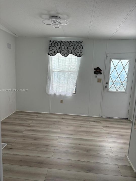 Interior space featuring light-toned wood-finish flooring, a multi-ring flush-mount ceiling light, and an exterior door with diamond-pattern glass inlay