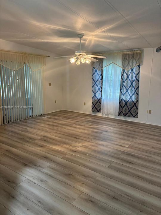 Wood-finish flooring, multi-panel sliding glass door, and ceiling fan with integrated five-light fixture