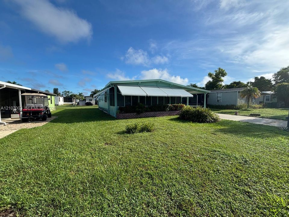 Exterior featuring a screen-enclosed porch, retractable awnings, brick skirting, and a concrete driveway